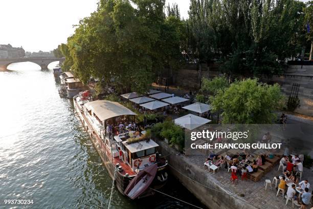 People sit on the banks of the Seine on July 7, 2018 in Paris as part of the Paris Plages summer event.