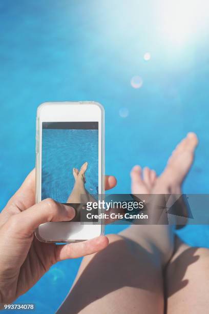 hand taking a picture in the swimming pool - feet selfie woman stockfoto's en -beelden