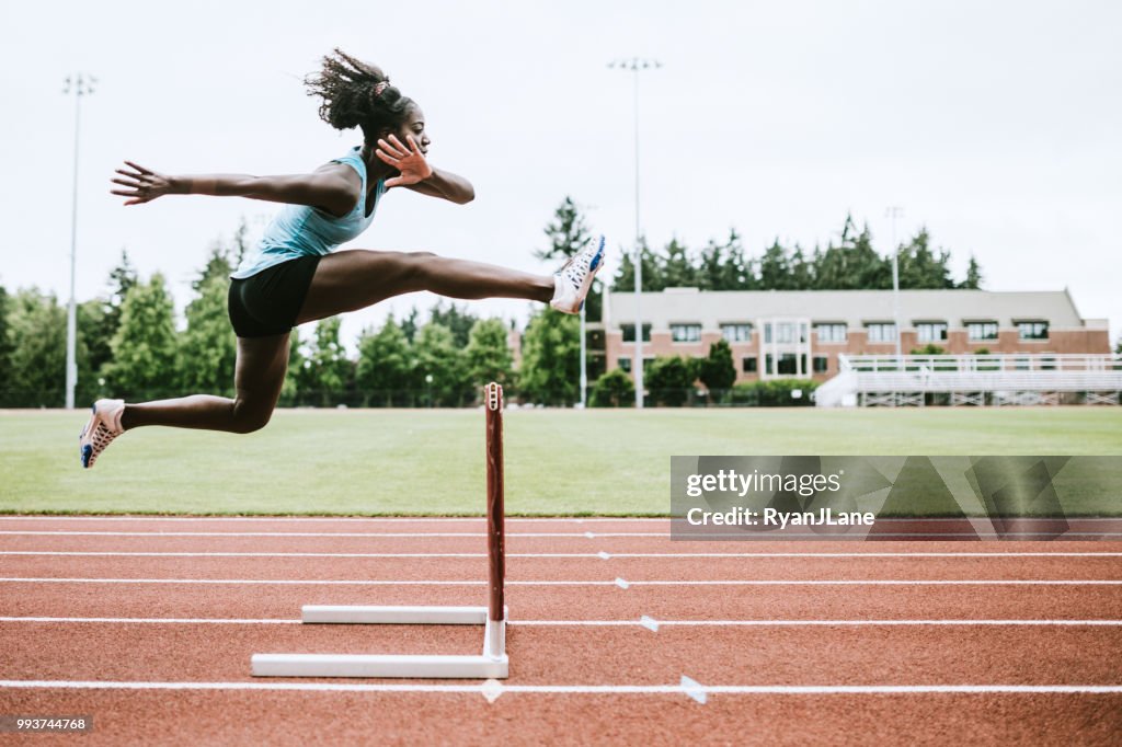 Atleta donna corre ostacoli per pista e campo