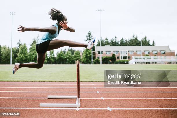 woman athlete runs hurdles for track and field - barreira imagens e fotografias de stock
