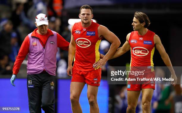 Lachie Weller of the Suns chats to Steven May of the Suns as he leaves the field injured during the 2018 AFL round 16 match between the North...