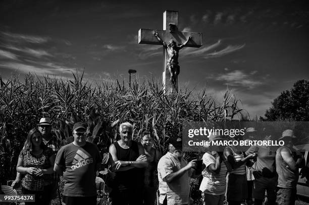 Spectators wait along the road by a calvary cross to watch riders during the first stage of the 105th edition of the Tour de France cycling race...