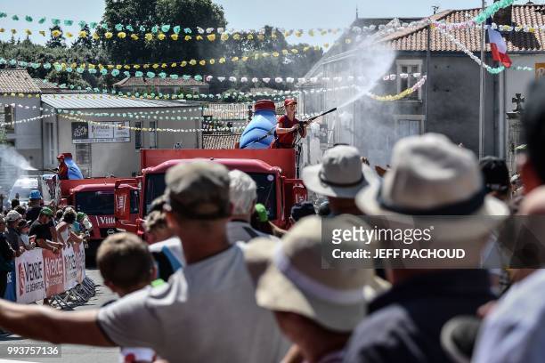 Young woman sprays refreshing water on spectators from a float of the race's publicity caravan, prior to the second stage of the 105th edition of the...