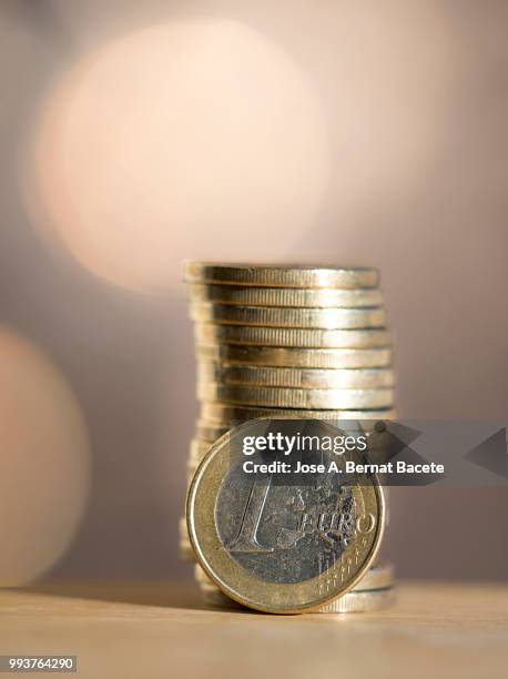 euro  coins arranged in heaps of different sizes, on a table illuminated by the light of the sun. - fünfzig euro cent stock-fotos und bilder