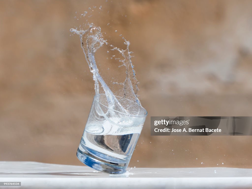 Impact of a glass of crystal with water that falls down on the soil.