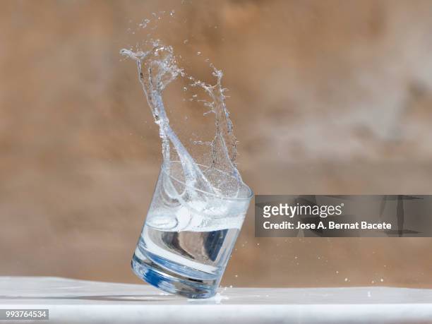 impact of a glass of crystal with water that falls down on the soil. - 高速度撮影 ストックフォトと画像