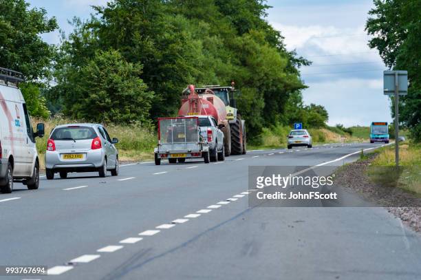 tractor pulling a trailer on a main scottish road - johnfscott stock pictures, royalty-free photos & images