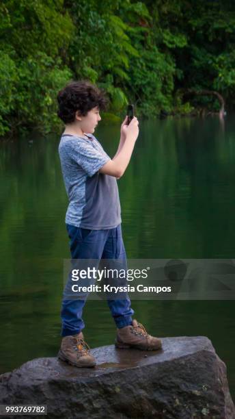 boy using mobile phone at tropical rainforest - alajuela stockfoto's en -beelden