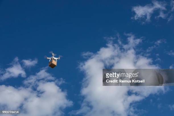 drone met het leveren van een kartonnen doos op een blauwe hemel - skybox stockfoto's en -beelden