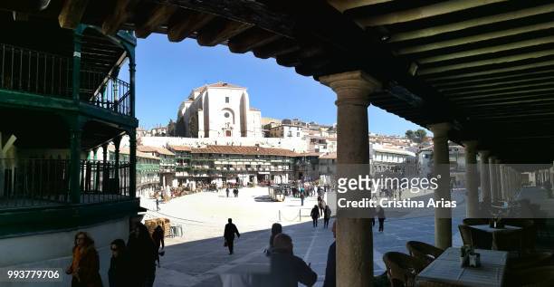 Plaza Mayor of Chinchon seen trough the arcades with the Church of Our Lady of the Assumption, Madrid, Spain.