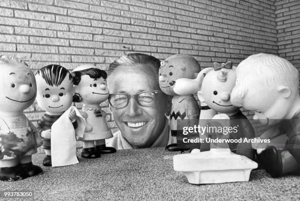 Portrait of American cartoonist Charles M Schultz surrounded by rubber doll replicas of the characters in his 'Peanuts' comic strip, California,...