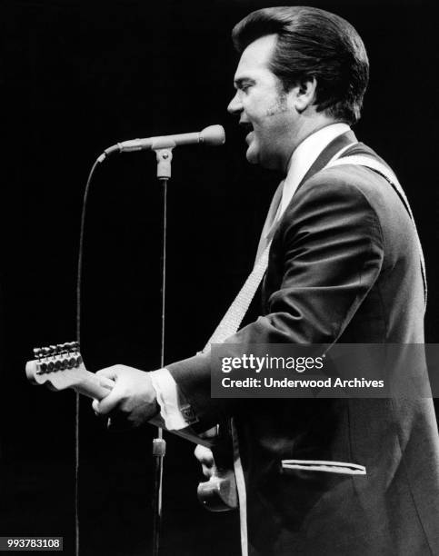 American Country musician Conway Twitty plays guitar as he performs onstage at Madison Square Garden, New York, New York, June 3, 1972.