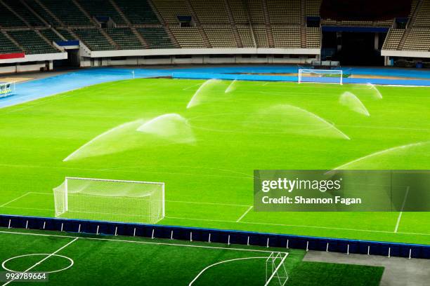 empty soccer field at night with water sprinkler system on - sprinkler system fotografías e imágenes de stock