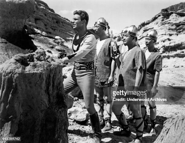 View of American actor Buster Crabbe , in costume as the title character in the serial 'Buck Rodgers' , along with unidentified cast members,...