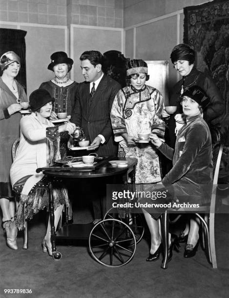 Italian opera singer tenor Tito Schipa , of the Chicago Civic Opera Company, shares cups of tea with unidentified women from Chicago's 'Gold Coast'...