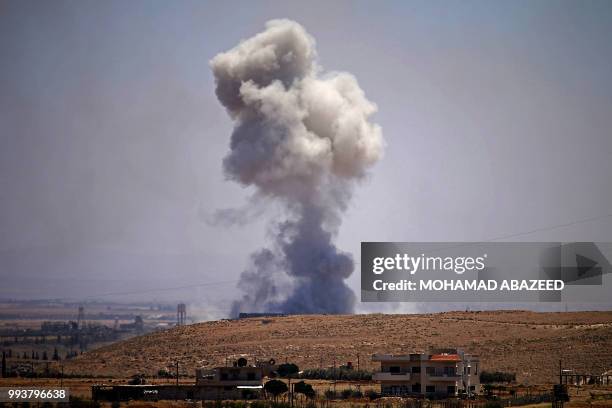 Smoke rises above rebel-held areas of the province of Daraa during reported airstrikes by Syrian regime forces on July 8, 2018. Syrian army soldiers...