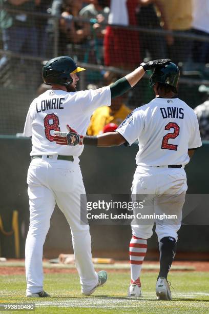 Jed Lowrie and Khris Davis of the Oakland Athletics celebrate after both scoring on a double hit by Stephen Piscotty of the Oakland Athletics in the...