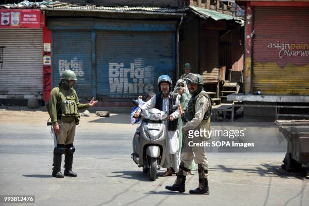 Indian policemen stops a scooterist during curfew imposed on the eve of the second death anniversary of the rebel commander Burhan Muzaffar Wani in...