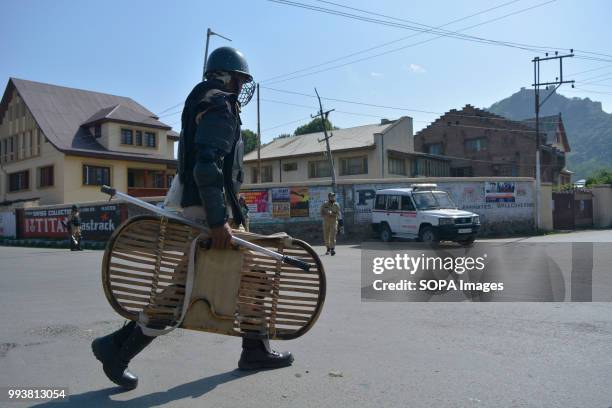 Indian paramilitary trooper patrols the deserted streets during curfew restrictions, on the second death anniversary of Burhan Muzaffar Wani a young...