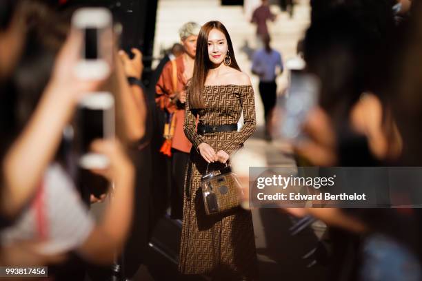 Jessica Jung wears a brown Fendi dress, a Fendi bag, and poses in front of fans outside Fendi, during Paris Fashion Week Haute Couture Fall Winter...