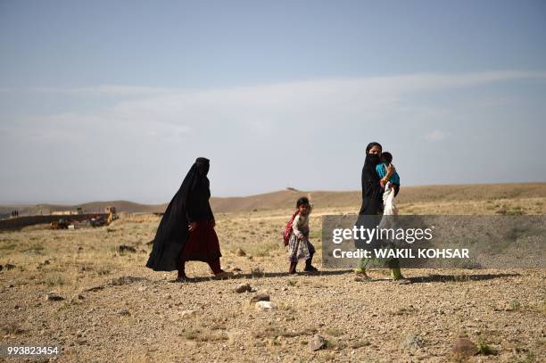 In this photo taken on July 7 Afghan women with children walks during a patrol by US Army from NATO with Afghan Commando against Islamic State...