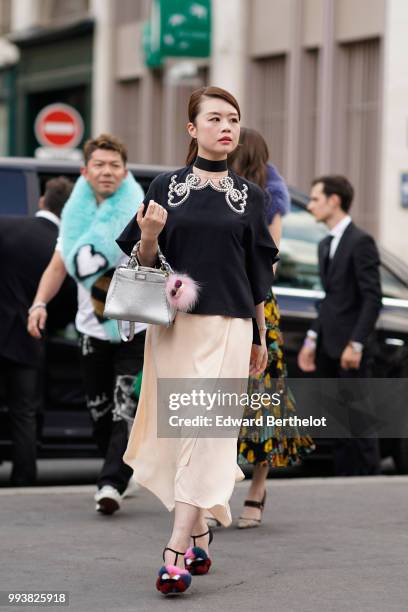 Guest wears a black choker, a black top with embroidered silver features, a silver glitter bag, a salmon colored skirt, pink fluffy shoes , outside...