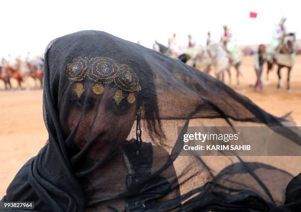 Moroccan girl from the southern desert performs during a fantasia as part of the 14th Tan-Tan Moussem Berber festival on July 08, 2018 in the western...