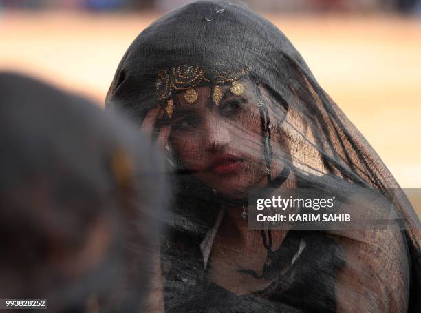 Moroccan girl from the southern desert performs during a fantasia as part of the 14th Tan-Tan Moussem Berber festival on July 08, 2018 in the western...