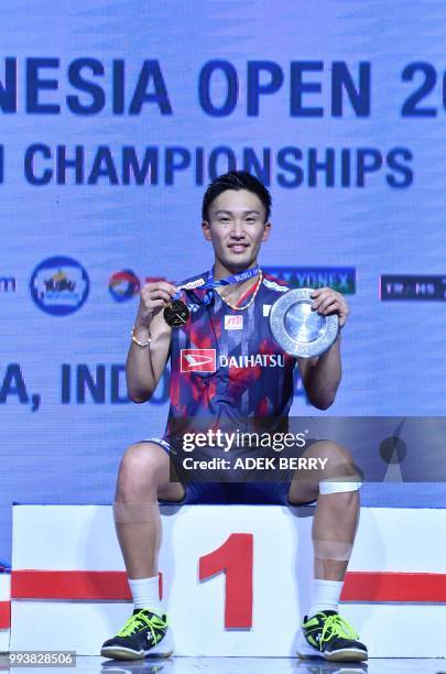 Winner Kento Momota of Japan poses for photographers after playing against Viktor Axelsen of Denmark during the men's singles badminton final match...