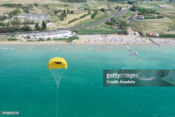 Drone photo shows that a man enjoys parasailing as people swim and sunbathe during a hot summer day at newly opened public beach on the shore of Van...