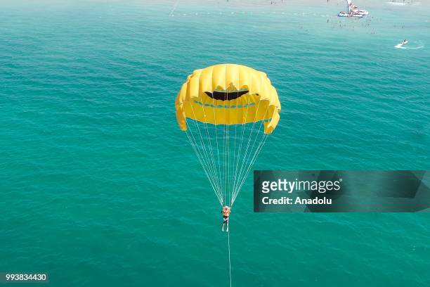 Drone photo shows that a man enjoys parasailing during a hot summer day at newly opened public beach on the shore of Van Lake on July 8, 2018 in Van,...