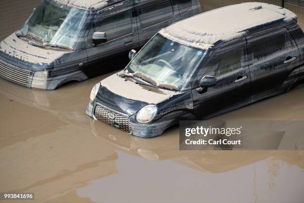 Cars lie partially submerged in floodwater following days of torrential rain, on July 8, 2018 in Kurashiki near Okayama, Japan. Over 70 people have...