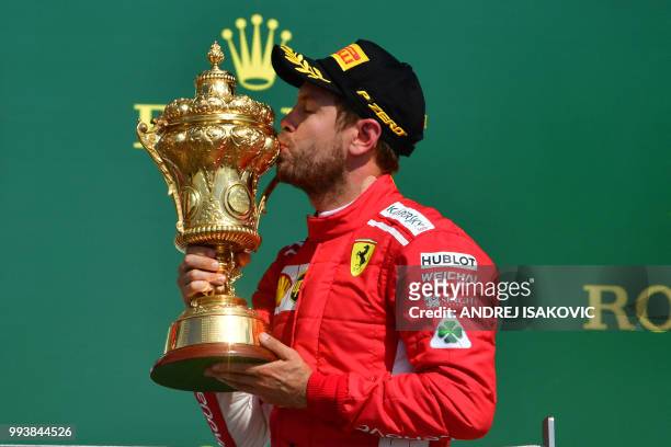 Ferrari's German driver Sebastian Vettel kisses his winner's trophy on the podium after the British Formula One Grand Prix at the Silverstone motor...