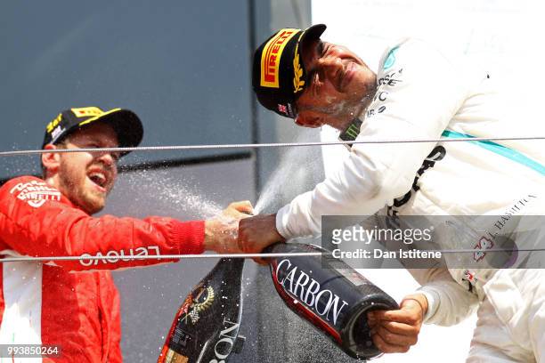 Race winner Sebastian Vettel of Germany and Ferrari celebrates with second placed finisher Lewis Hamilton of Great Britain and Mercedes GP on the...