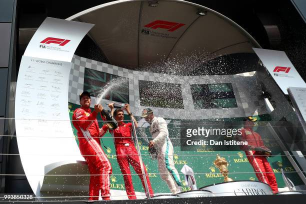 Race winner Sebastian Vettel of Germany and Ferrari celebrates on the podium with second place finisher Lewis Hamilton of Great Britain and Mercedes...