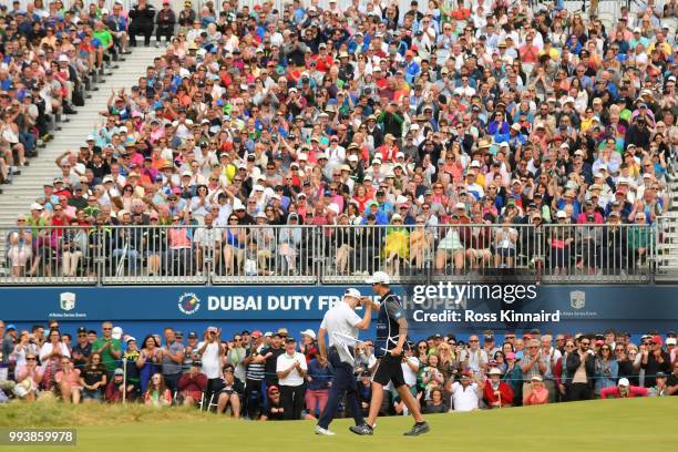 Russell Knox of Scotland celebrates holing a birdie putt on the 18th green with his caddie during the final round of the Dubai Duty Free Irish Open...