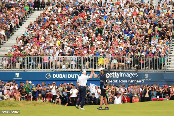 Russell Knox of Scotland celebrates holing a birdie putt on the 18th green with his caddie during the final round of the Dubai Duty Free Irish Open...