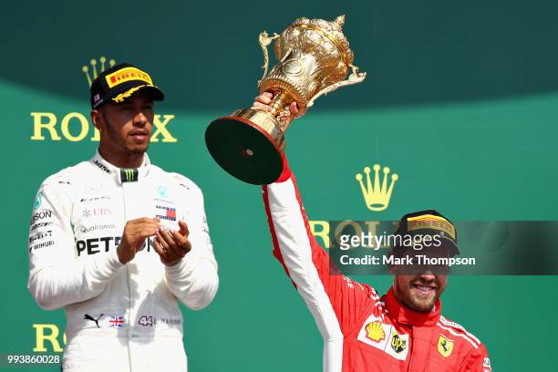 Race winner Sebastian Vettel of Germany and Ferrari celebrates on the podium as second place finisher Lewis Hamilton of Great Britain and Mercedes GP...