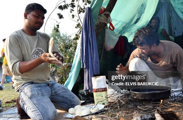 Group of migrant men cook a meal over an open fire, in front of their improvised tent in a makeshift migrant camp outside the western-Bosnian town of...