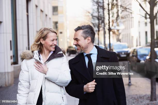 happy wealthy couple walking the city streets in winter - mature couple winter outdoors stockfoto's en -beelden