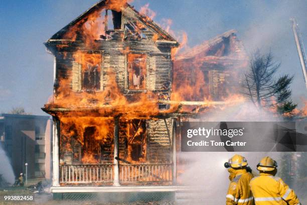 firefighters fighting ahose fire that is totally engulfed in flames - engulfed stock pictures, royalty-free photos & images