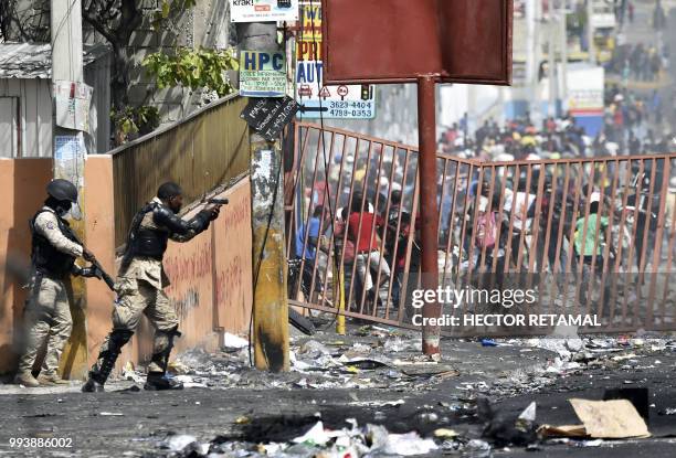 Member of the Haitian police points his gun at people to avoid looting in shops in Delmas, a commune near Port au Prince during protests against the...