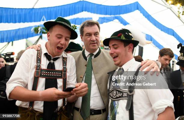 Two men in traditional Bavarian costums take a photo with Markus Soeder , Prime Minister of Bavaria, in a beer tent during the celebration of the...