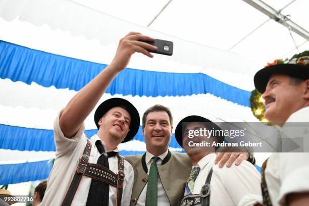 Two men in traditional Bavarian costums take a photo with Markus Soeder , Prime Minister of Bavaria, in a beer tent during the celebration of the...