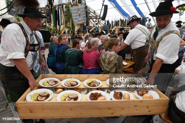 People in traditional Bavarian costums sit in a beer tent and order food during the 125th anniversary of the local Gebirgstrachten-Erhaltungsverein...