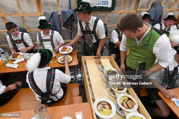 People in traditional Bavarian costums sit in a beer tent and order food during the 125th anniversary of the local Gebirgstrachten-Erhaltungsverein...