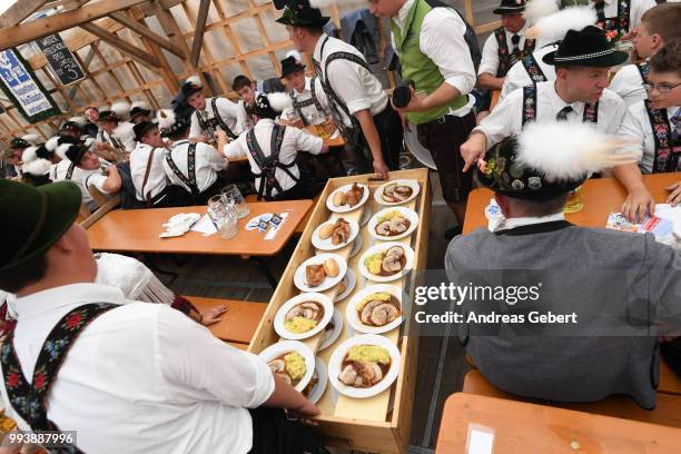 People in traditional Bavarian costums sit in a beer tent and order food during the 125th anniversary of the local Gebirgstrachten-Erhaltungsverein...