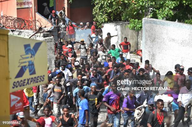Looters flee when Haitian police arrive to control the situation at a store in Delmas, a commune near Port-au-Prince, during protests against the...
