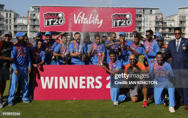 Champagne is sprayed as India's players celebrate with the series trophy after the third international Twenty20 cricket match between England and...