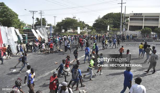 Residents and looters flee when Haitian police arrive in Delmas, a commune near Port-au-Prince, during protests against the rising price of fuel, on...